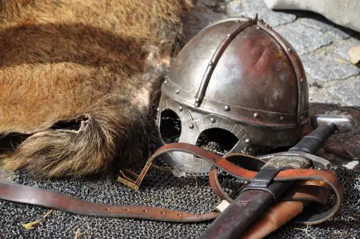 black steel helmet near black and gray handle sword